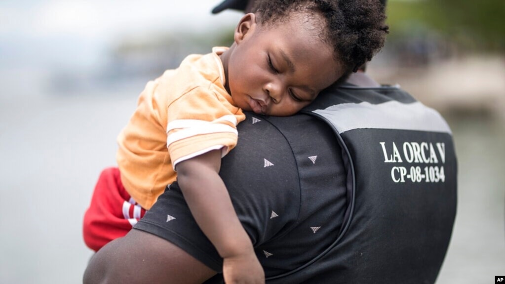 Un migrante haitiano sostiene a su hijo