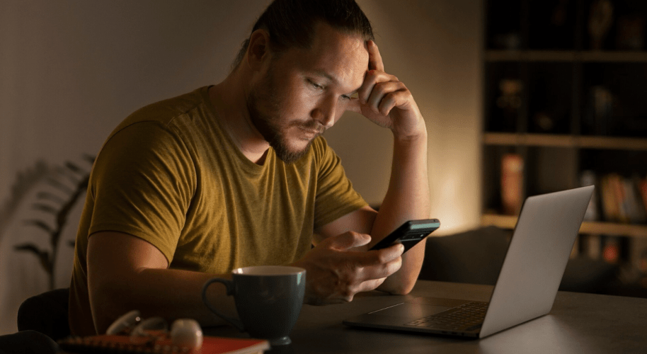 Persona frente al celular y computadora