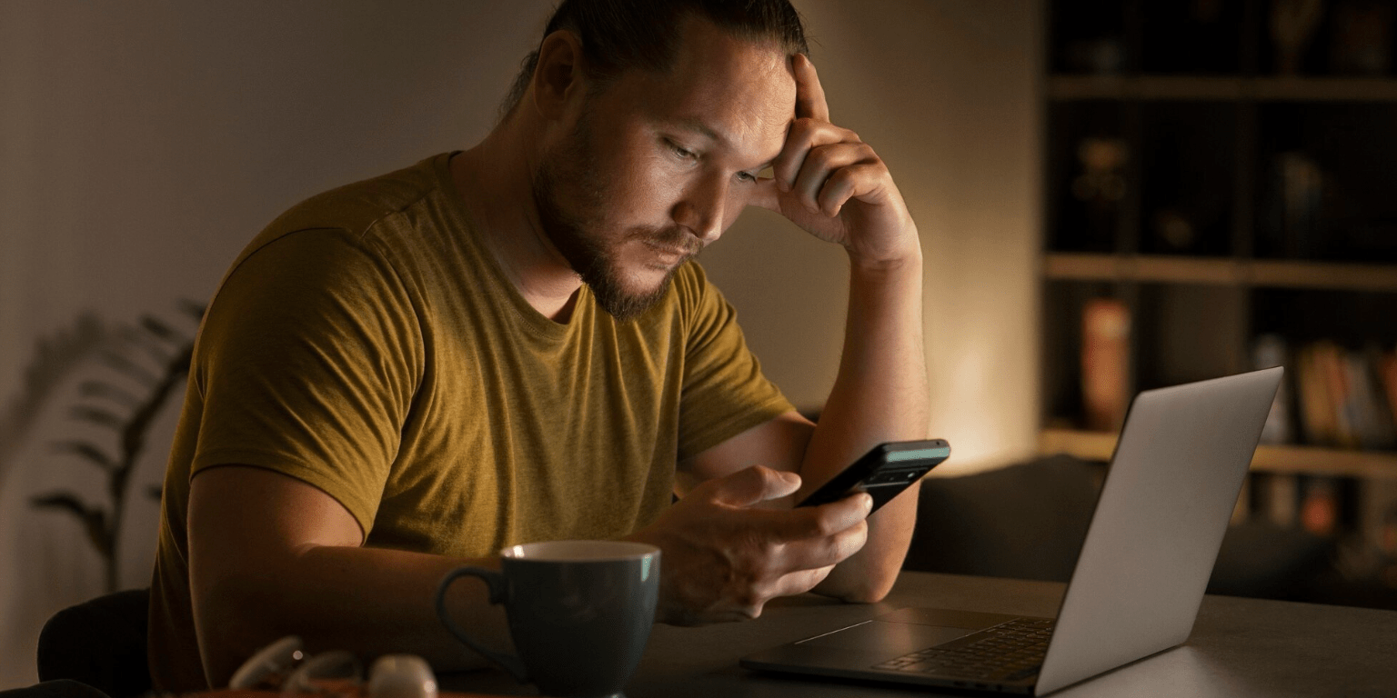Persona frente al celular y computadora