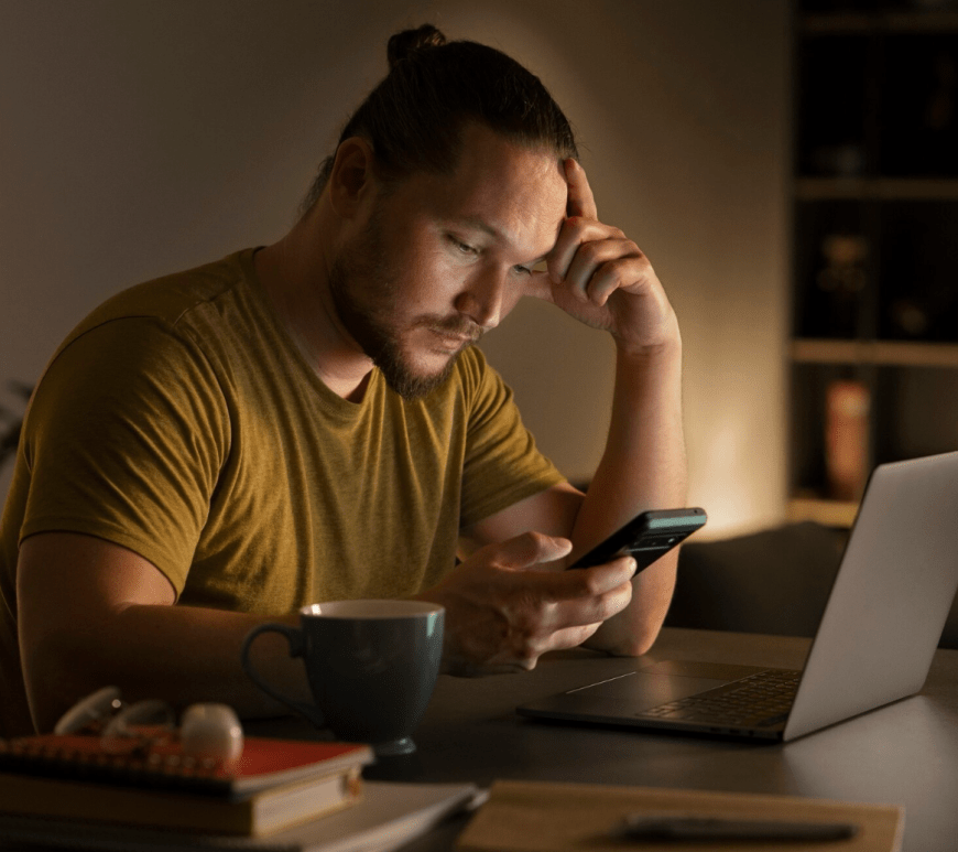 Persona frente al celular y computadora
