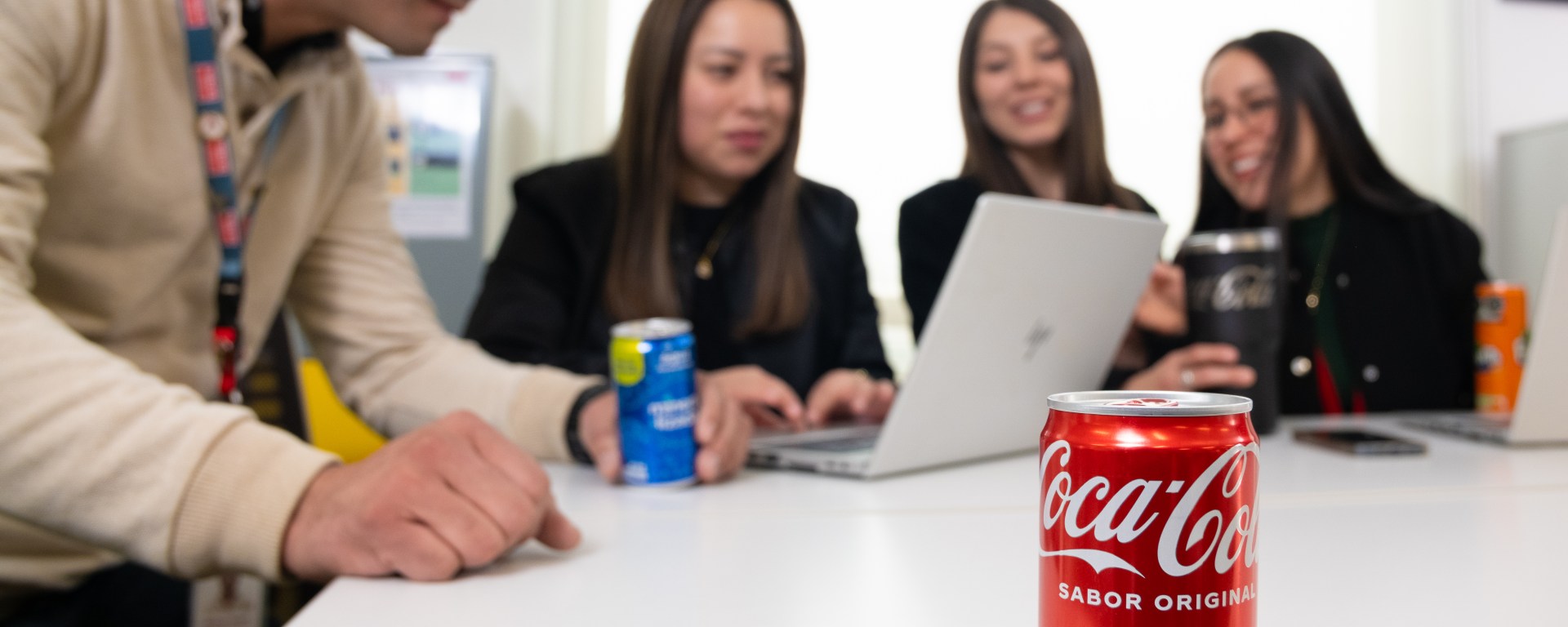 Personas en escritorio de trabajo con una coca cola