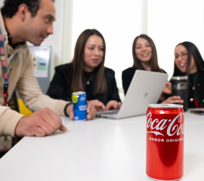 Personas en escritorio de trabajo con una coca cola