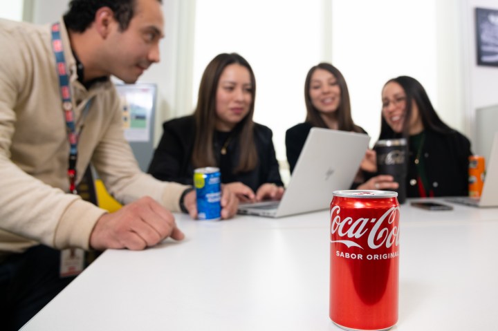 Personas en escritorio de trabajo con una coca cola 