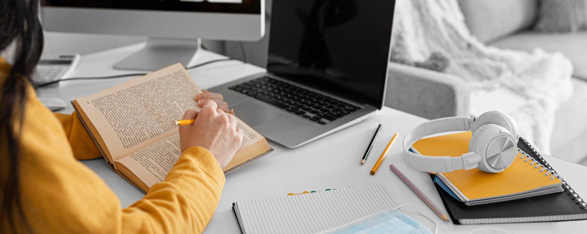 Persona con libreta, libro y computadora