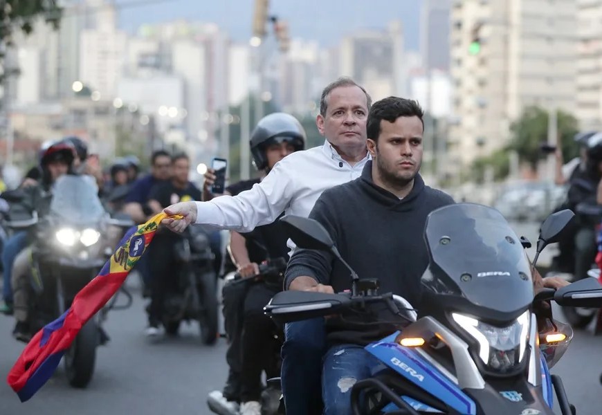 El exdiputado Juan Pablo Guanipa (i) sostiene una bandera de Venezuela durante una caravana tras ser excarcelado este domingo, en Caracas (Venezuela). EFE/ Ronald Peña R