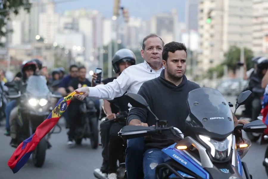 El exdiputado Juan Pablo Guanipa (i) sostiene una bandera de Venezuela durante una caravana tras ser excarcelado este domingo, en Caracas (Venezuela). EFE/ Ronald Peña R