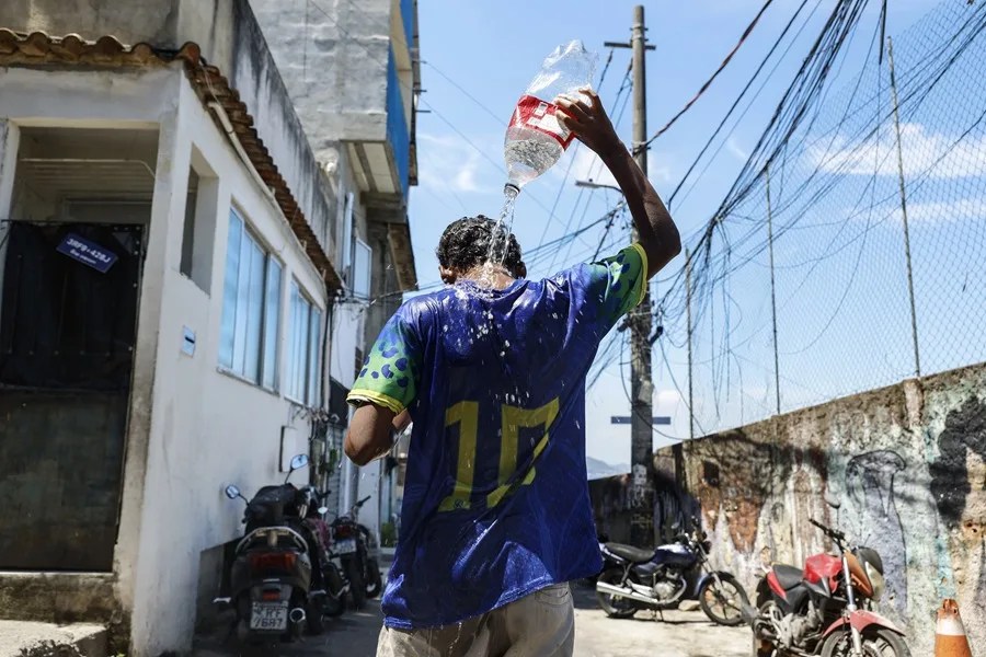 Un joven se baña en las calles de la favela de Tavares Bastos en Río de Janeiro (Brasil). EFE/ Antonio Lacerda/ Archivo