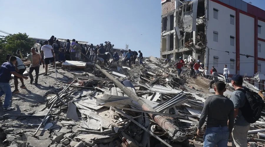 Personas caminan sobre los escombros de un edificio colapsado este lunes, en Cali (Colombia). EFE/ Ernesto Guzmán