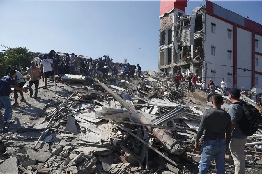 Personas caminan sobre los escombros de un edificio colapsado este lunes, en Cali (Colombia). EFE/ Ernesto Guzmán