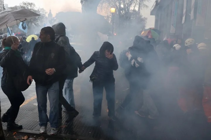 Personan son afectadas por el gas lacrimógeno durante una manifestación contra un proyecto de ley impulsado por el Gobierno del ultraliberal Javier Milei que introduce cambios en los procesos de desalojo, expropiaciones y uso de tierras quemadas, este jueves en Buenos Aires (Argentina). EFE/ Juan Ignacio Roncoroni