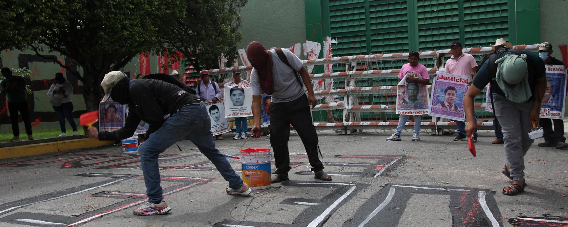 Personas encapuchadas pintan fuera del 27 Batallón de Infantería en el marco de las protestas por el 12 aniversario de la desaparición de los 43 estudiantes de Ayotzinapa, este miércoles en Iguala, en Guerrero (México). Un grupo de estudiantes de la Escuela Normal Rural de Ayotzinapa lanzó bombas caseras contra instalaciones militares en Iguala (Guerrero, sur), en protesta por la falta de respuestas sobre la desaparición de los 43 normalistas, ocurrida hace casi 12 años, el 26 de septiembre de 2014. EFE/ José Luis De La Cruz