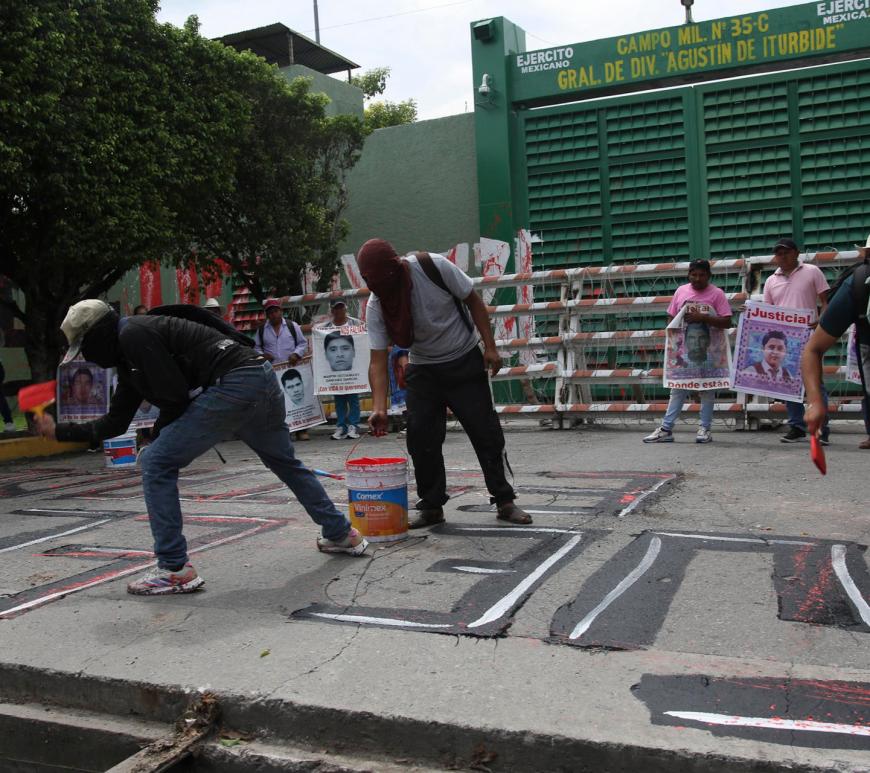 Personas encapuchadas pintan fuera del 27 Batallón de Infantería en el marco de las protestas por el 12 aniversario de la desaparición de los 43 estudiantes de Ayotzinapa, este miércoles en Iguala, en Guerrero (México). Un grupo de estudiantes de la Escuela Normal Rural de Ayotzinapa lanzó bombas caseras contra instalaciones militares en Iguala (Guerrero, sur), en protesta por la falta de respuestas sobre la desaparición de los 43 normalistas, ocurrida hace casi 12 años, el 26 de septiembre de 2014. EFE/ José Luis De La Cruz