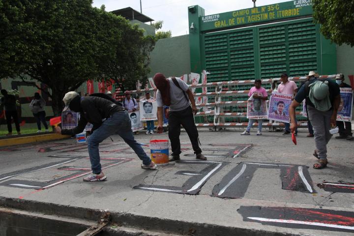 Personas encapuchadas pintan fuera del 27 Batallón de Infantería en el marco de las protestas por el 12 aniversario de la desaparición de los 43 estudiantes de Ayotzinapa, este miércoles en Iguala, en Guerrero (México). Un grupo de estudiantes de la Escuela Normal Rural de Ayotzinapa lanzó bombas caseras contra instalaciones militares en Iguala (Guerrero, sur), en protesta por la falta de respuestas sobre la desaparición de los 43 normalistas, ocurrida hace casi 12 años, el 26 de septiembre de 2014. EFE/ José Luis De La Cruz