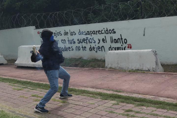 MEX3490. IGUALA (MÉXICO), 23/09/2026.- Un hombre encapuchado lanza una bomba casera al interior del 27 Batallón de Infantería, este miércoles en Iguala, Guerrero (México). Un grupo de estudiantes de la Escuela Normal Rural de Ayotzinapa lanzó bombas caseras contra instalaciones militares en Iguala (Guerrero, sur), en protesta por la falta de respuestas sobre la desaparición de los 43 normalistas, ocurrida hace casi 12 años, el 26 de septiembre de 2014. EFE/ José Luis De La Cruz